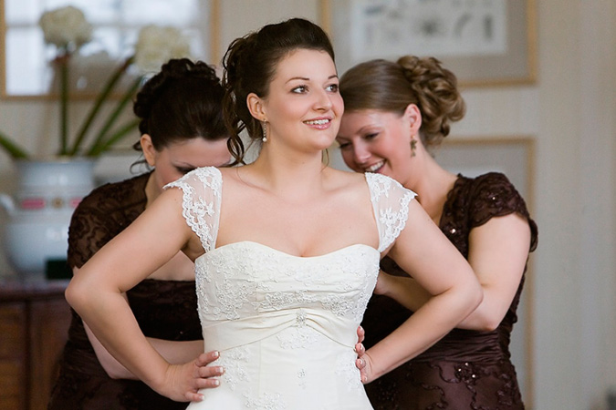 novia con damas de honor ayudándola a cerrar su vestido de boda por la espalda
