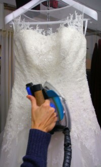 vestido de novia colgado en percha siendo planchado