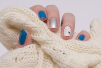 mano con manicura azul cogiendo lana blanca